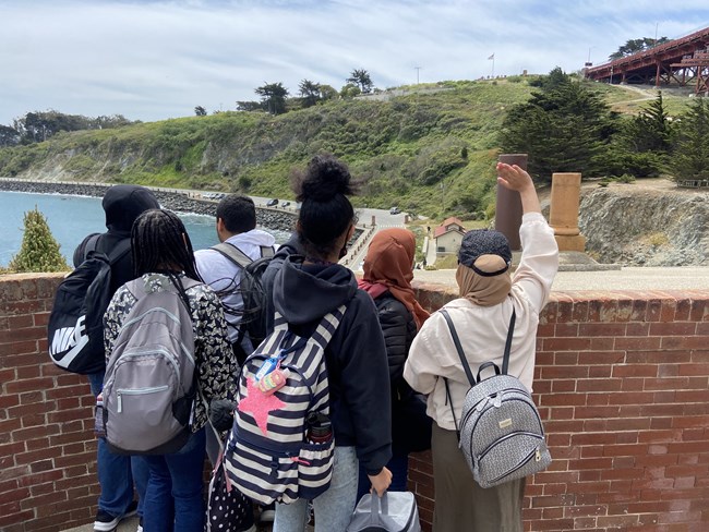A group of students takes in the view from the top of Fort Point.