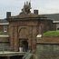 Sandstone gatehouse stands in front of the entrance to Fort Jay.
