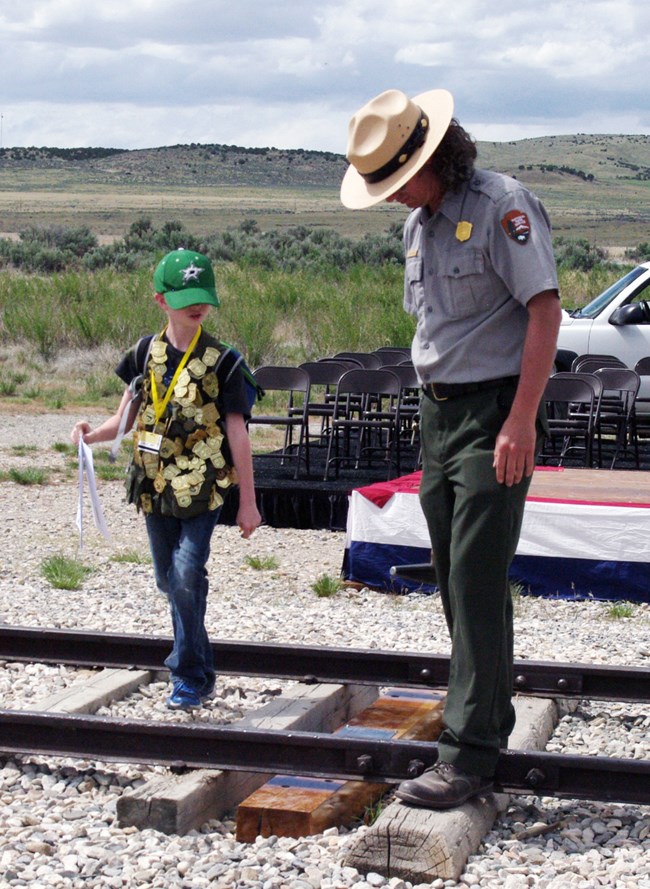 A ranger stands at the last spike site with a Jr Ranger.