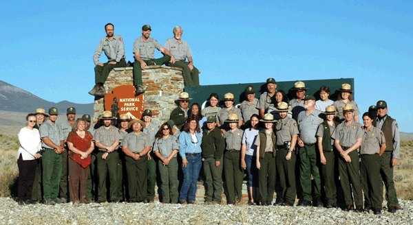 park staff in front of visitor center sign