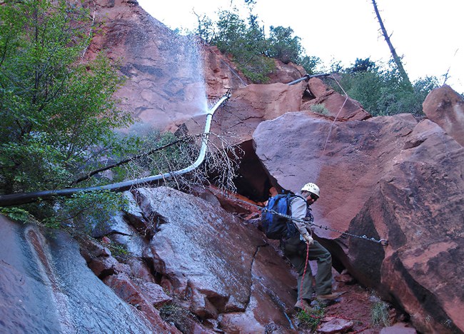A park ranger uses rock climbing equipment to access a remote break in the Transcanyon waterline.