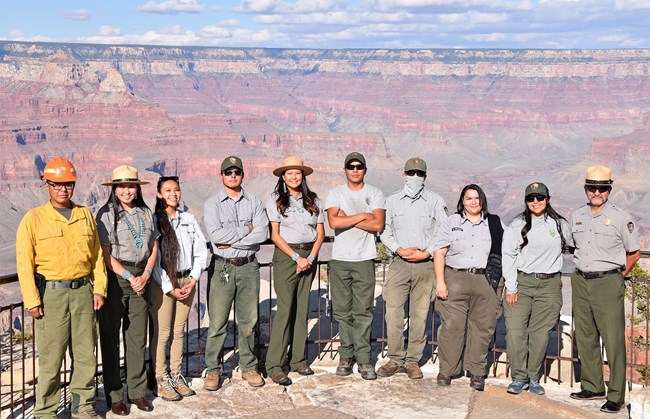 10 National Park Service Employees pose for a group photo at a scenic overlook with Grand Canyon in the background
