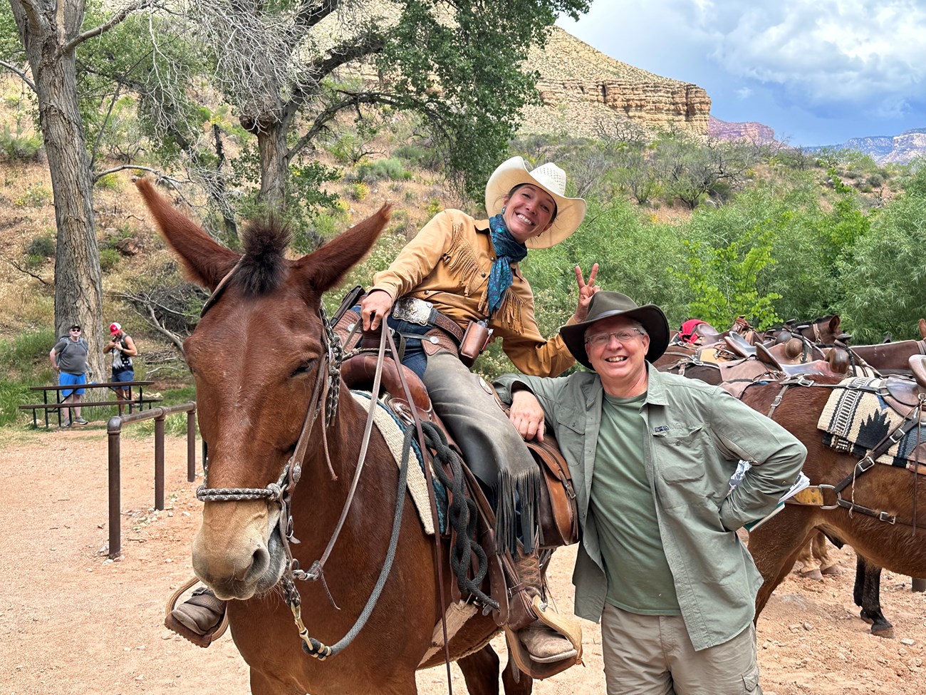 A man stands next to a woman on a mule.