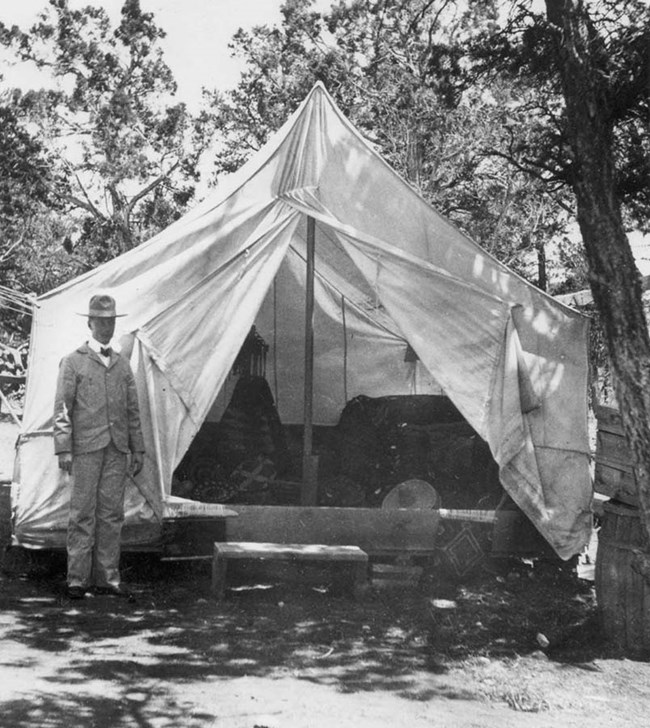 Early entrepeneur in front of large white tent in the woods
