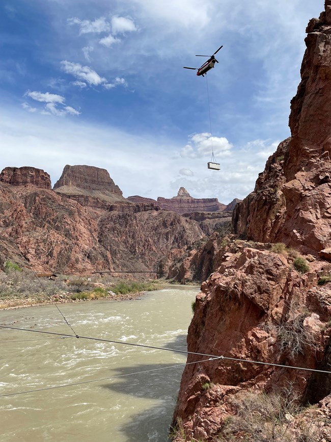 A helicopter transfers a load of equipment containing a connex box into the inner canyon at Grand Canyon National Park.