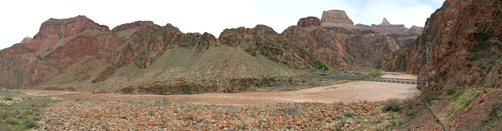 River Trail and Silver Bridge A trail linking to a large bridge spanning across the Colorado River with tall canyon walls on either side.