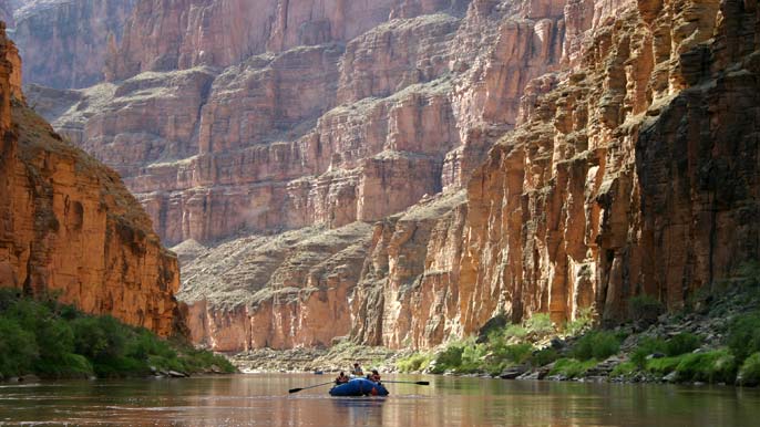 Boat in distance on Colorado River. Canyon walls.