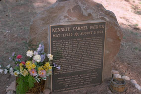 gravestone on large boulder with flowers on side