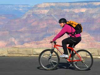 Grand Canyon Active Trails Bike Ride shows one rider on road with Grand Canyon in the background.
