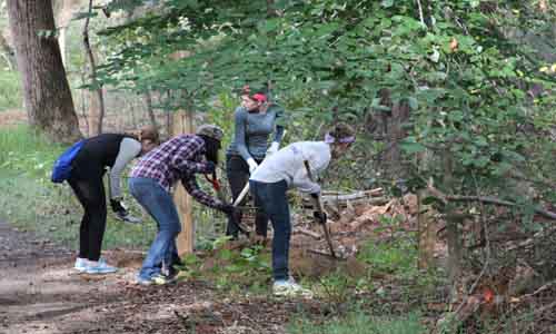 The girl scouts of Greenbelt help place sand near the exercise equipment