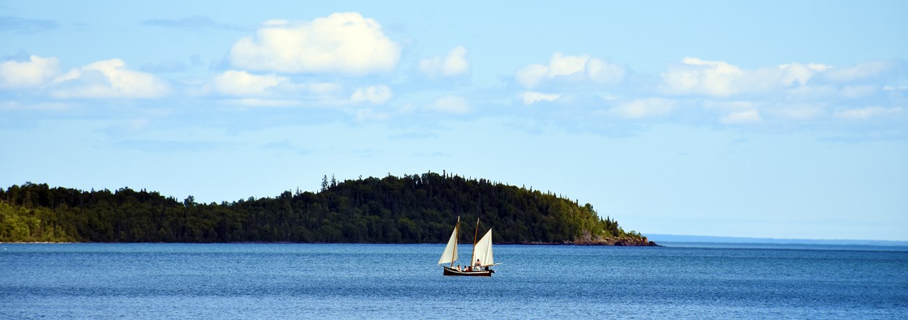 Historic sailboat on a bay in front of an island.
