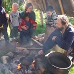 Kids watch our traditional birchbark canoe builder pop wild rice in a fry pan over the fire.