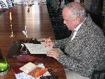 Re-enactor Bob Braun composes a letter in the Great Hall Grand Room at the partner's cherry table.