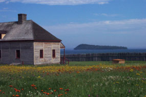 The Great Hall overlooks Grand Portage Island among fields of yellow and orange hawkweed.