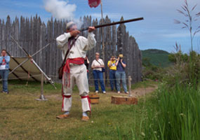 An interpreter in period dress demonstrates loading and firing a flintlock musket.