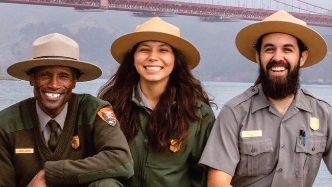 Three NPS rangers in uniform smiling