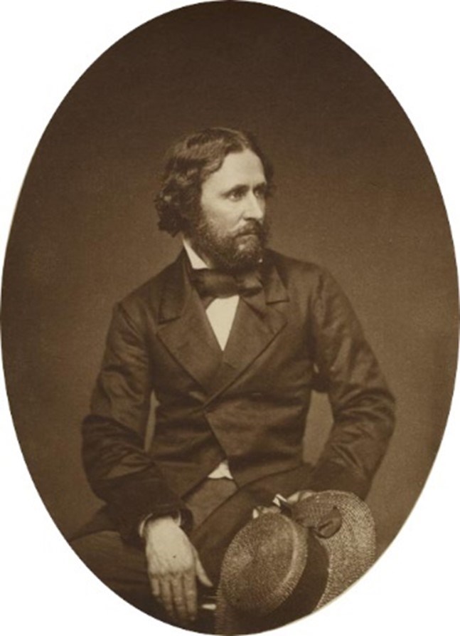 An oval black and white historic photo of John C. Fremont, a bearded man with a suit and bow tie.