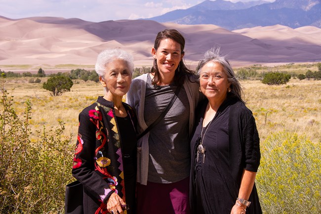 Three generations of Konishi Women stand in front of the dunes