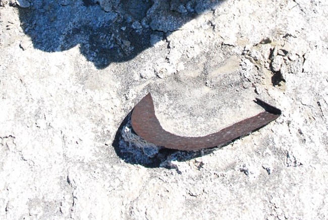 An old rusted shovel blade is partially buried in white alkali deposits.