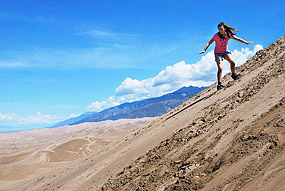 Girl Sandboarding on High Dune Summit