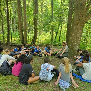 Ranger and students sitting in a circle in the grass.