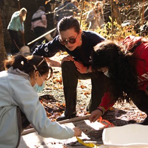 Ranger and two students looking at creatures in a bucket.