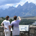 Visitors at the Snake River Overlook pointing at the mountains.