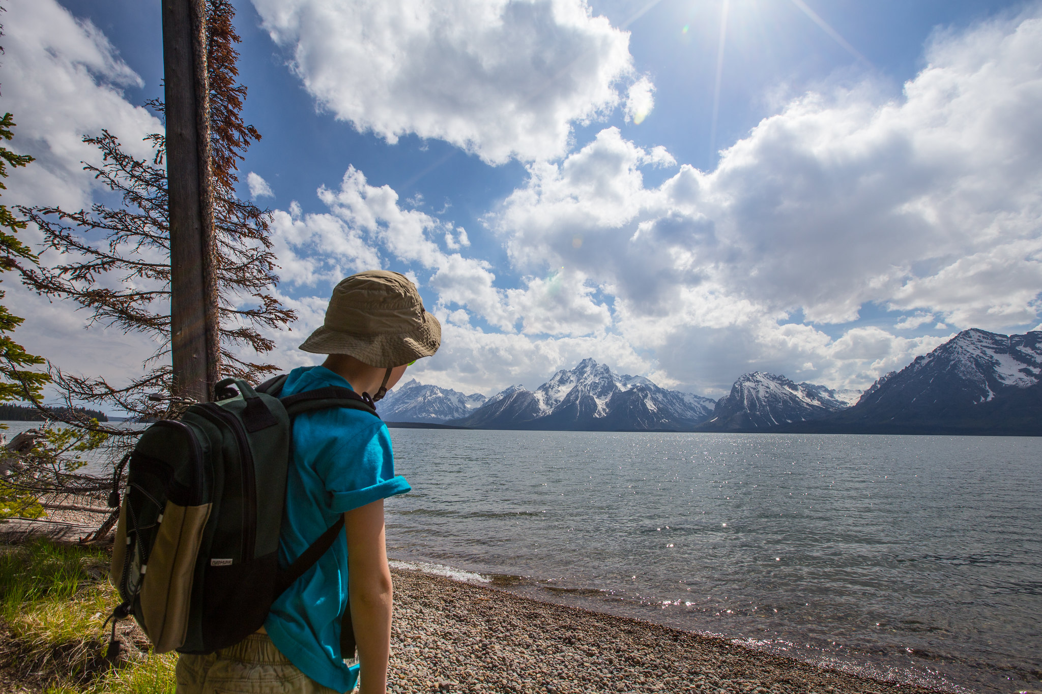 A youth looks at the Tetons over the lake.