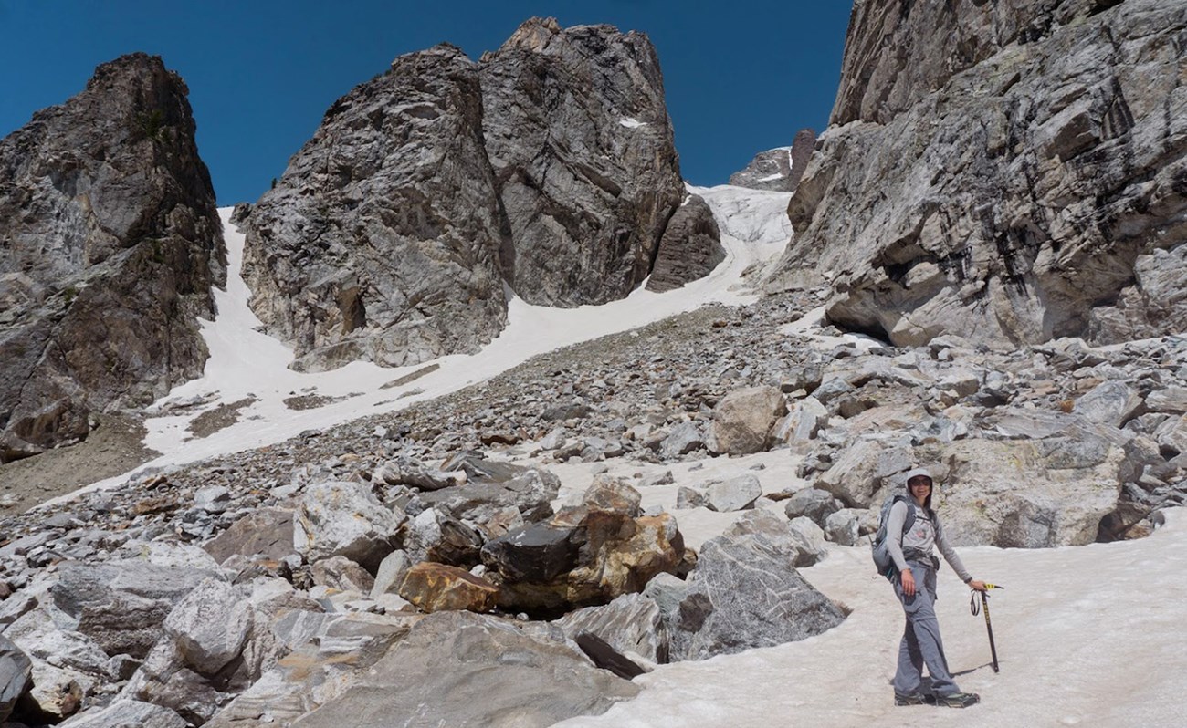 A woman holding an ice axe stands on a glacier.