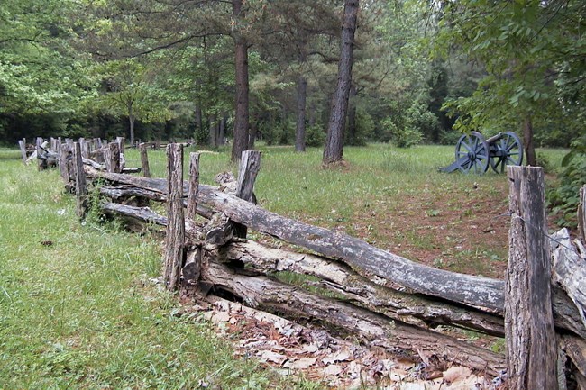 Split rail fence, six-pounder cannon on a forested battlefield