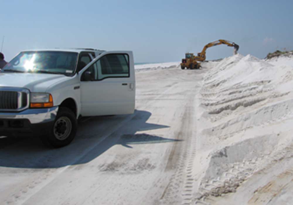 Equipment operators removes white sand from the J. Earle Bowden Road on Santa Rosa Island.&nbsp;