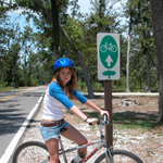 A female visitor on her bike is next to the Live Oaks Bicycle Route sign. A female visitor on her bike is next to the Live Oaks Bicycle Route sign.