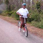 A female visitor rides her bike on a paved bike path. A female visitor rides her bike on a paved bike path.