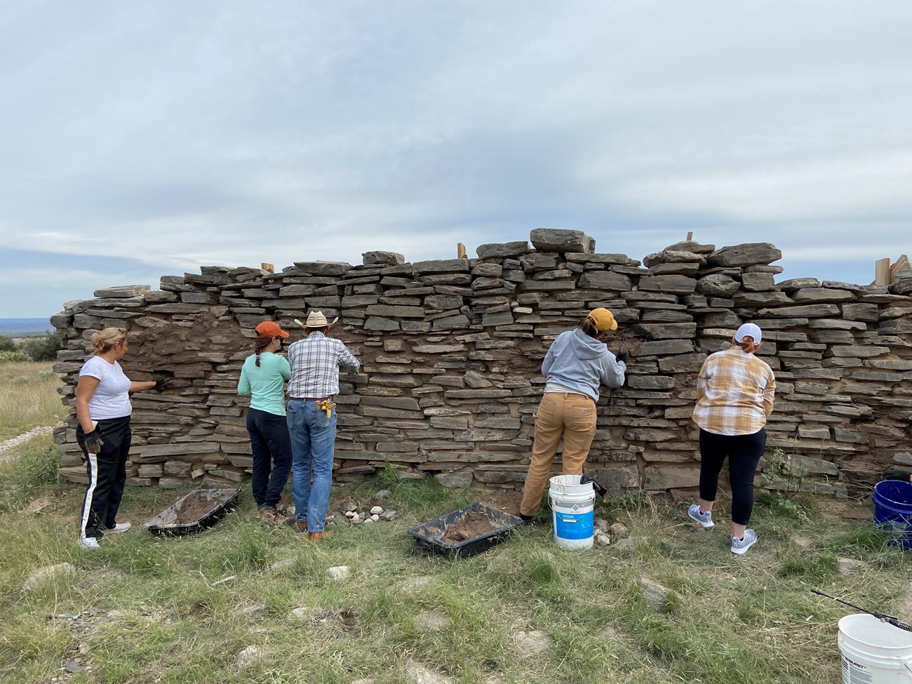 Students work on a tall stone wall