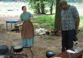 Vanessa Smiley welcomes a visitor to her cooking fire at the Farmer's Market living history program.
