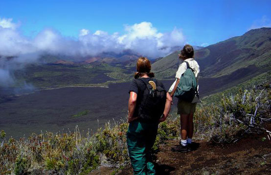 Two hikers look back at the volcanic landscape they have covered on their wilderness hike.