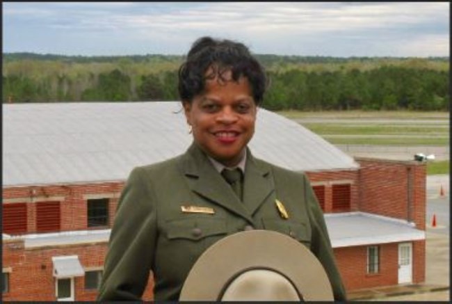NPS employee can be seen in image holding a flat hat.