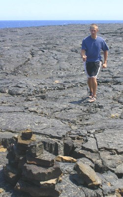 Drew crosses the pahoehoe lava, following the ahu (cairns).