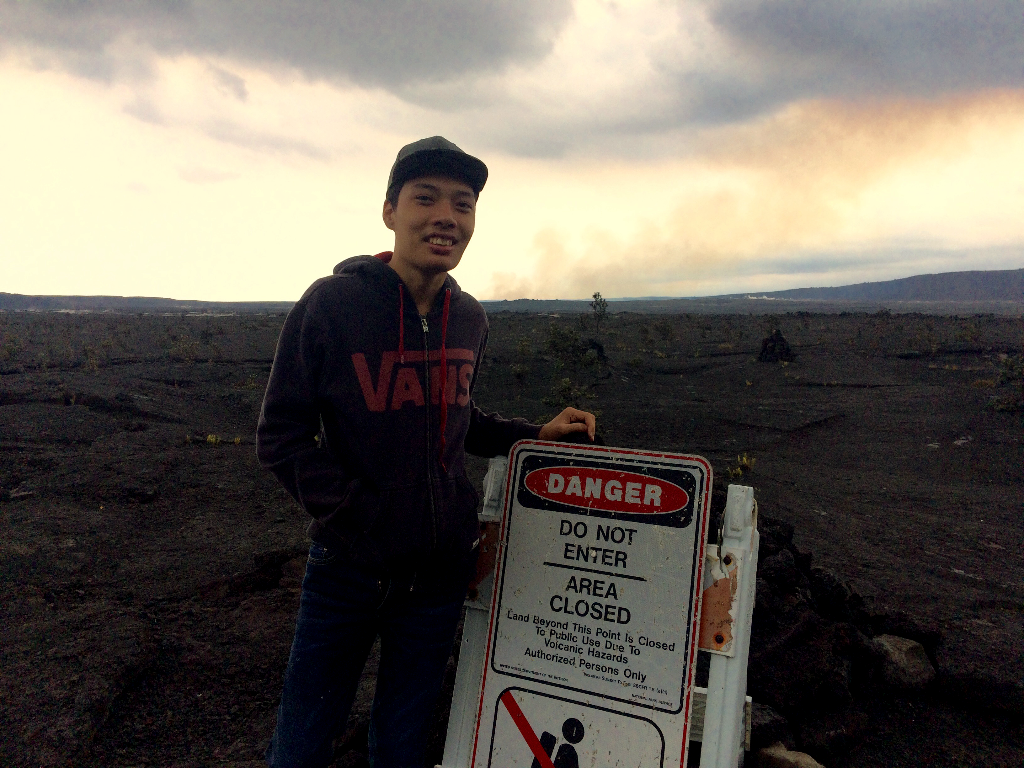 Visitor stands behind closure sign enjoying views of the caldera