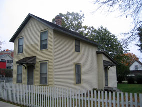 A yellow two story house with a white picket fence.