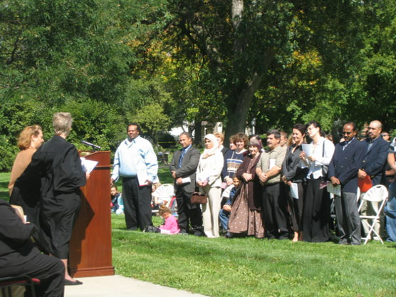 A federal judge and new citizens in an outdoor ceremony.