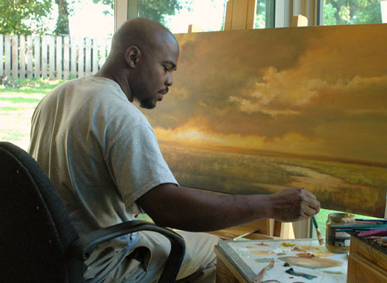 A man paints a landscape in his art studio.