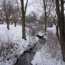 Trees and snow-covered banks along a creek.