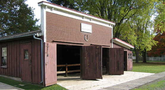 Exterior of a wood frame blacksmith shop with a brown facade and white trim.