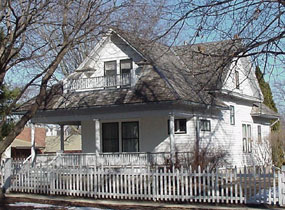 White house with a porch and picket fence.
