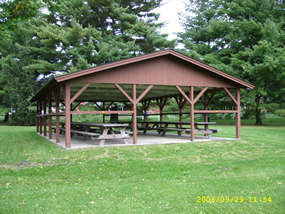 The east shelter is a brown wooden structure sheltering picnic tables.