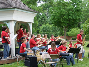 A high school band performs at a park gazebo.