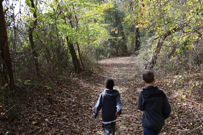 two kids hiking through forest on nature trail