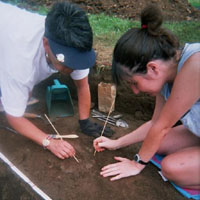 Teachers excavate pottery from an archeological feature.