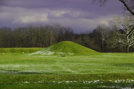 A tall grass-covered mound under a dark grey sky.